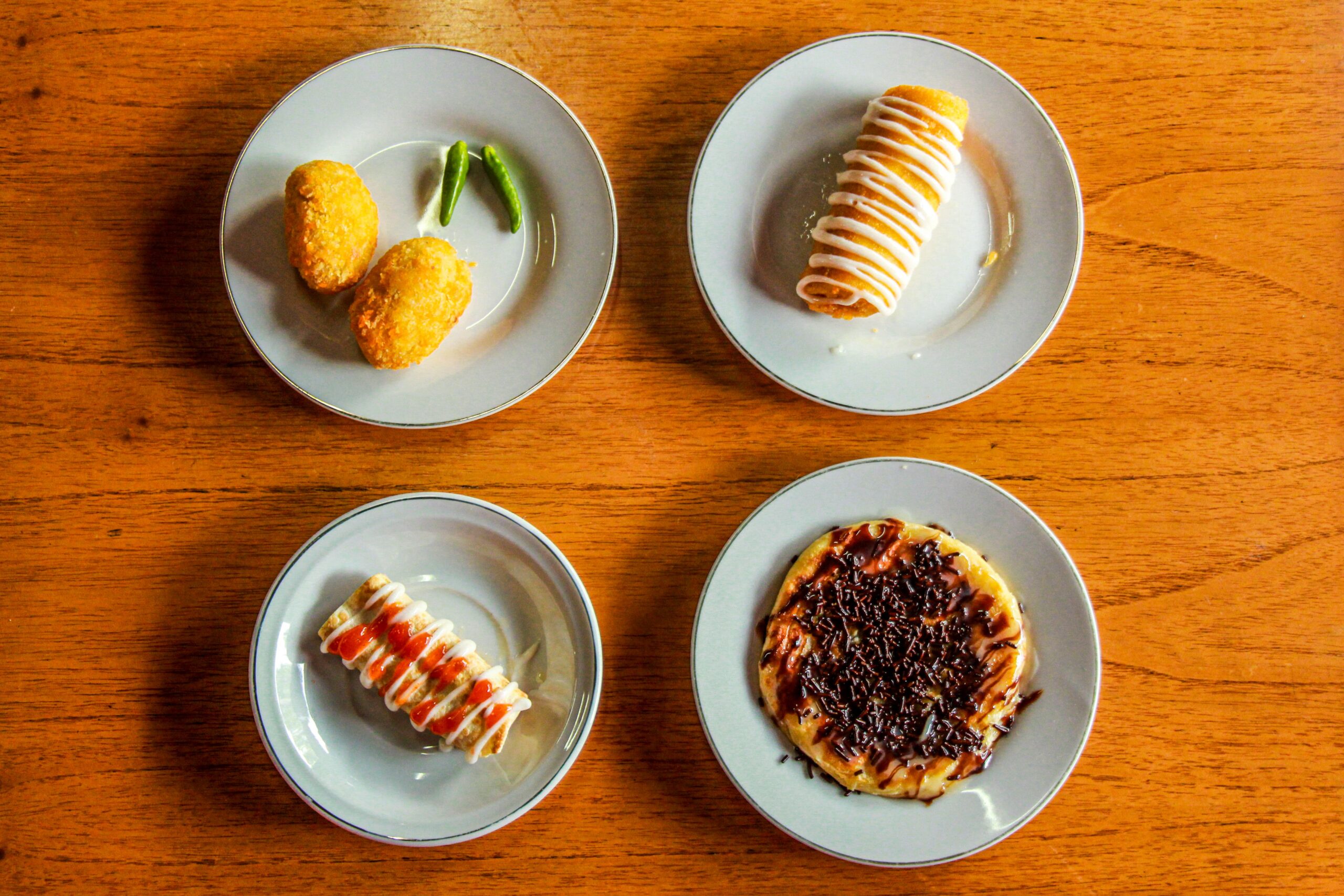 Delicious assortment of snacks displayed on white plates placed on a wooden table.